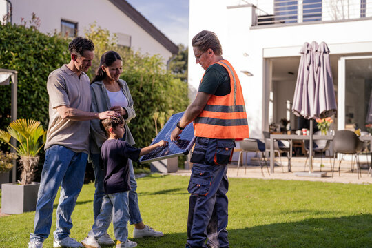 Installer consulting family about solar energy system in garden