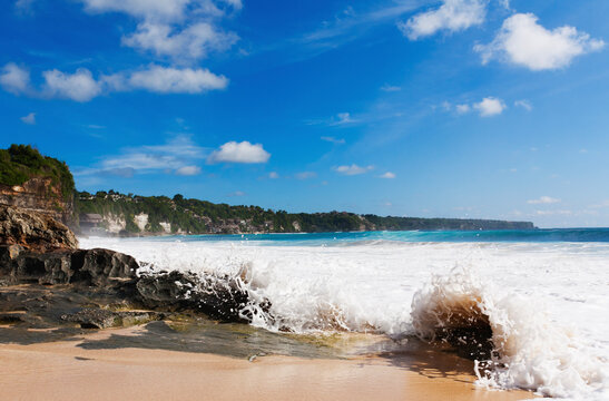 Waves crashing on Dreamland Beach coast in Bali Indonesia under blue sky