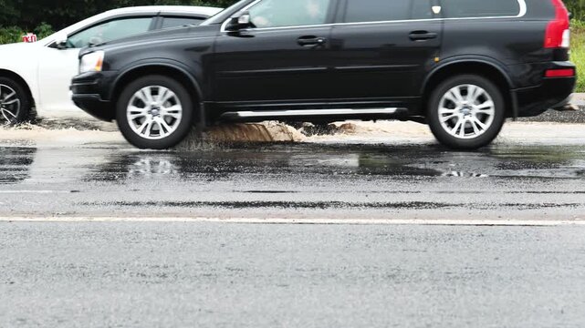 Driving cars splashing water while commuting on a wet road during a rainy day