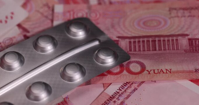 Chinese money for one hundred yuan and pills in a packaged blister, medicines and red Chinese cash with a face value of 100 yuan