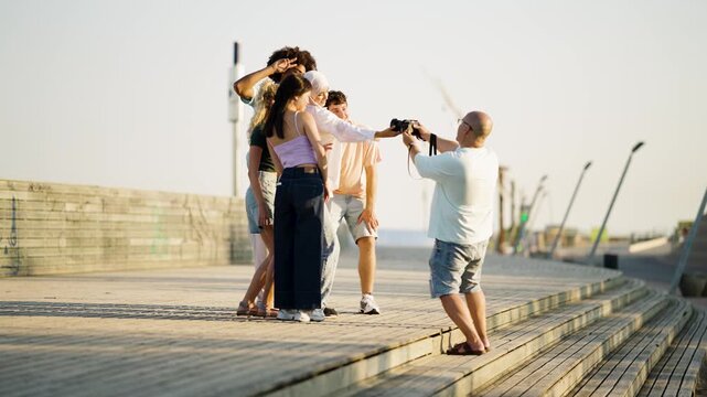 Professional photographer working with a diverse group of young friends during an outdoor photoshoot. The models are posing together at sunset