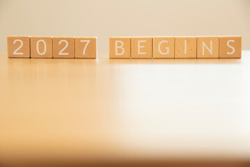 Wooden cube blocks 2027 begins background. Texts and numbers on wooden blocks with copy space. 2026 happy new year idea concept.