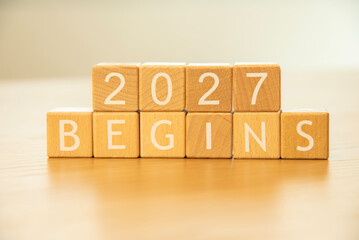 Wooden cube blocks 2027 begins background. Texts and numbers on wooden blocks with copy space. 2026 happy new year idea concept.