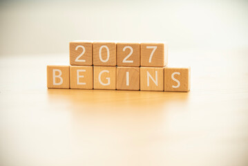 Wooden cube blocks 2027 begins background. Texts and numbers on wooden blocks with copy space. 2026 happy new year idea concept.