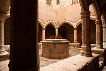 empty cloister courtyard with an antique well and clay pots