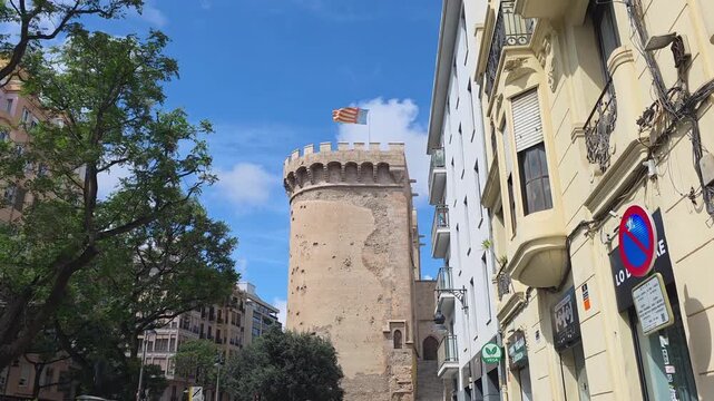 view of The flag of Valencia (Reial Senyera)  and the Torres de Quart (Quart Towers), one of the two remaining gates of the old city wall of Valencia, Spain.