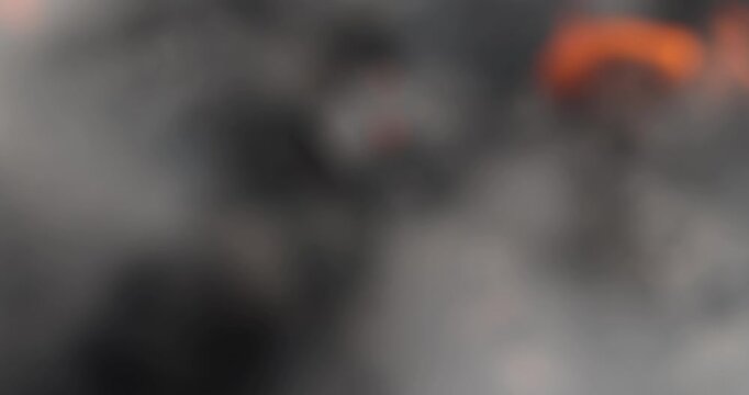 a campfire made of logs with a lot of smoke during the preparation of the barbecue for cooking meat, steaming briquettes of charcoal in the grill during the lighting of the fire