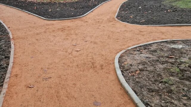 newly constructed or renovated park pathway. Path self-binding gravel path decomposed granite orange beige color, which contrasts well with surroundings.​Edging path is clearly defined by concrete cur