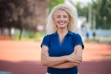 Confident mature woman smiling at camera on track field