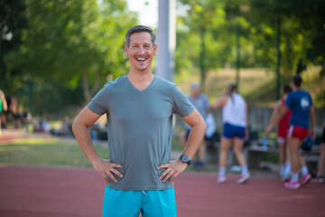 Fototapeta premium Smiling man standing on track field at sports training