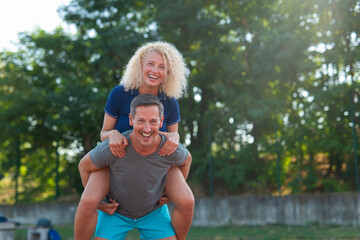Joyful couple piggyback riding outdoors enjoying active lifestyle