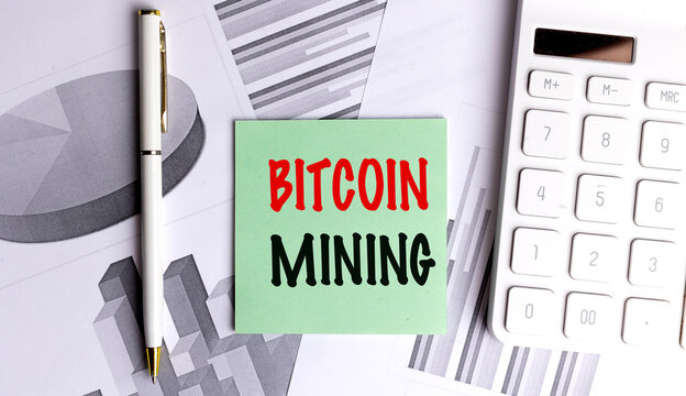 Green card text bitcoin mining on office desk with charts, pen, and calculator, symbolizing cryptocurrency generation - Powered by Adobe