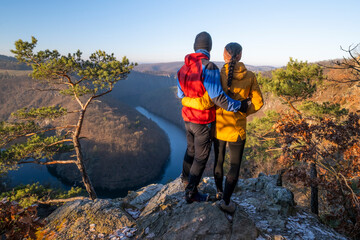 A couple in love stands in an embrace on a viewpoint above the river Vltava in Czech Republic