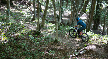 Electric mountain bike rider navigating a forest trail with sunlight and trees