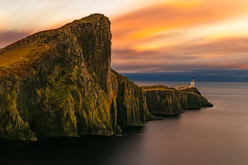 Neist Point lighthouse on dramatic sea cliffs at sunset, Isle of Skye, Scotland, long exposure ocean, colorful sky and rugged coastline, iconic travel landscape.