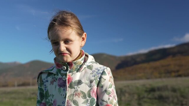 Young girl child nature close-up portrait of a kid making grumpy and silly faces outside on a beautiful autumn day.