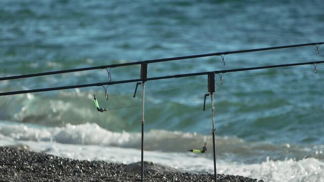 Fishing ocean beach. Waiting on rod pod for bite by strong waves on rocky shore.