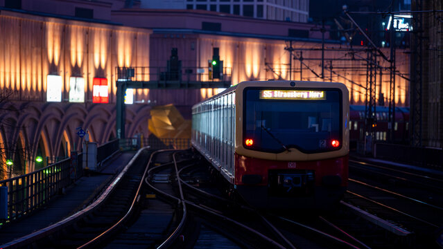 Berlin, Germany - December 26, 2025: Red S-Bahn train S5 to Strausberg Nord arriving at the illuminated Alexanderplatz station at dusk