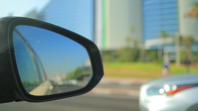 View in the side rearview mirror of a car driving on the city street.
Arabic caption: Objects in mirror are closer than they appear.