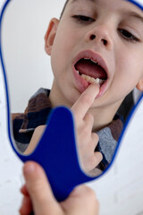 A boy looks at his teeth in the mirror, takes care of his mouth and undergoes a dental examination