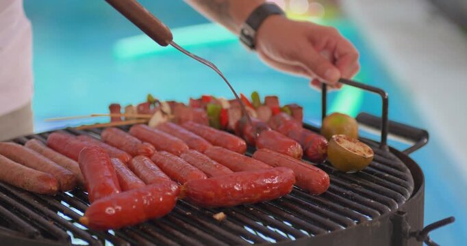 Grill with chorizo and skewers by pool at sunset