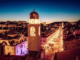 Aerial view of the illuminated bell tower and Stradun street, the main thoroughfare, casting a warm glow against the deepening twilight, Dubrovnik, Dubrovnik-Neretva County, Croatia.