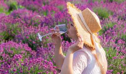 Woman with a glass of wine having a picnic in a lavender field at sunset