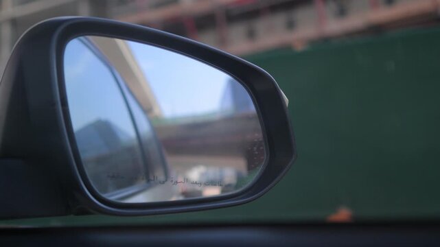 View in the side rearview mirror of a car driving on the city street.
Arabic caption: Objects in mirror are closer than they appear.