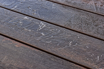 Exotic wood panels covered with a thin layer of ice during black ice conditions.