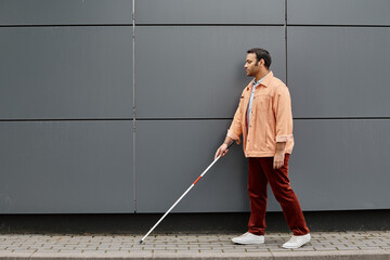 Confident Indian man navigating urban landscape with a cane during a sunny day
