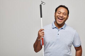 Handsome Indian blind man radiates joy while holding his cane in bright studio light