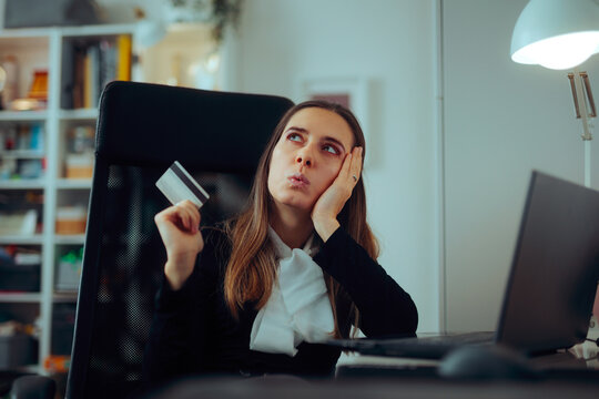 Woman Holding a Credit Card  Thinking about Buying Something.  Puzzled lady thinking about spending money on online shopping website
