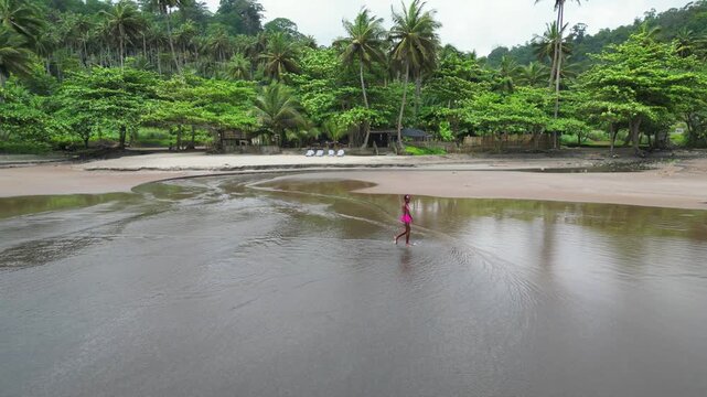 Image of an African girl walking along the seashore at 7 ondas beach, and palm trees in the background.S&atilde;o Tom&eacute; e Principe,Africa
