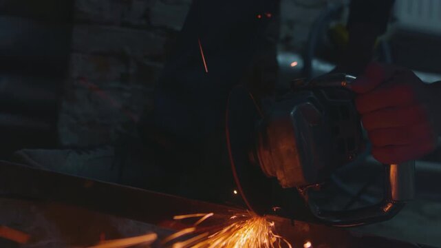 Sparks fly from cutting metal with angle or electric grinder. Metal turning disc cuts the material. Detail shot of cutting iron with circular saw. Welder is working steel at industrial plant.
