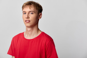 Young man in a red shirt stands against a neutral background, a casual studio shot showcasing...