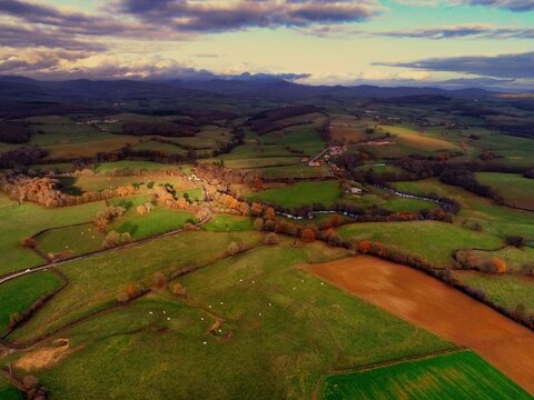 Aerial view of rolling green pastures meet the distant hills under a dramatic sky, Morvan, Morvan, France.