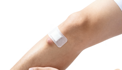 Applying medical tape over a small sterile dressing on adult leg lump showcasing precise and safe bandage placement against clean white background.