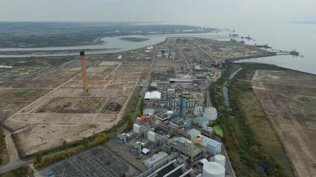 Aerial shot of large power plant, with derelict industrial site in background, sub station pylons electrical energy generation, London Gateway Port, UK