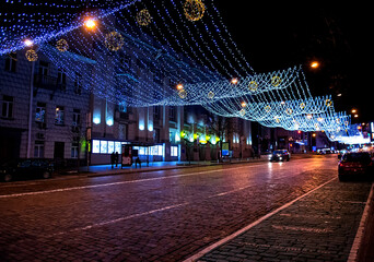 Night city street decorated with festive holiday lights illuminated buildings and moving cars creating vibrant urban Christmas atmosphere and winter celebration mood