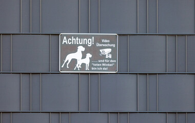 Warning sign for video surveillance and guard dogs on a modern privacy screen