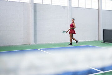 Obraz premium Female pickleball player walking on indoor court with paddle