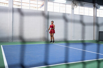 Female pickleball player preparing to serve on indoor court