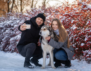 Para młodych ludzi na spacerze z psem w parku robi sobie selfie ze swoim pupilem