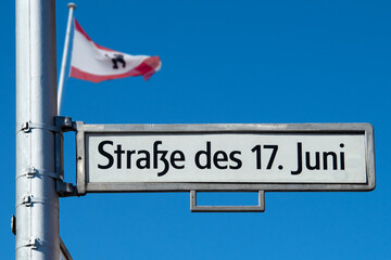 Stra&szlig;e des 17. Juni, Stra&szlig;enschild in Berlin mit Berlinflagge im Hintergrund