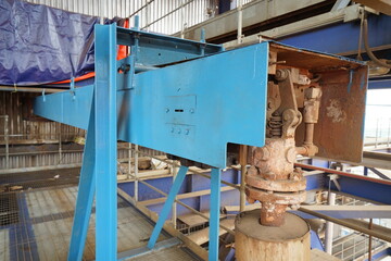 Industrial machinery detail featuring a robust blue metal structure and a complex mechanical assembly, essential for material handling or processing within a factory environment