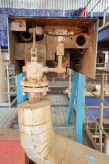Detailed view of an industrial control valve and pipe assembly with thermal insulation, showcasing complex machinery within a factory or manufacturing plant environment