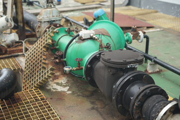 Industrial water pump system with large pipes and green machinery on a wet surface