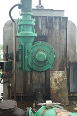 Industrial machinery with a robust green electric motor and gearbox system, connected by intricate piping, vital for power transmission and efficiency in a manufacturing plant