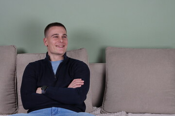 portrait of a handsome young man smiling and relaxing on couch