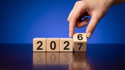 A human hand delicately interacts with wooden blocks displaying the numerals 2027 representing future planning and aspirations for the coming year